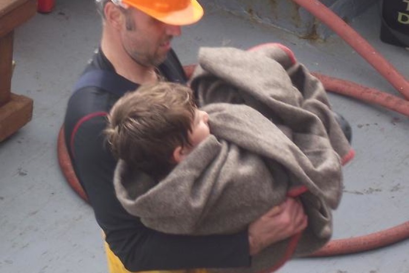 Crew member Juan Owens helps the boy ashore