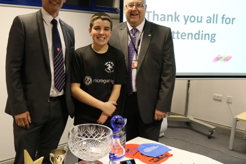 The Minister and HSBC's Kevin Cartledge with swimmer Ben Grainger and some of the trophies and medals he has won since taking part in the Games.